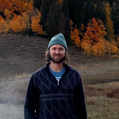 man standing in forest in front of autumn leaves