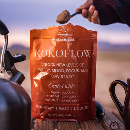 Kokoflow package with a spoonful of powder held above it, set against a blurred natural background.